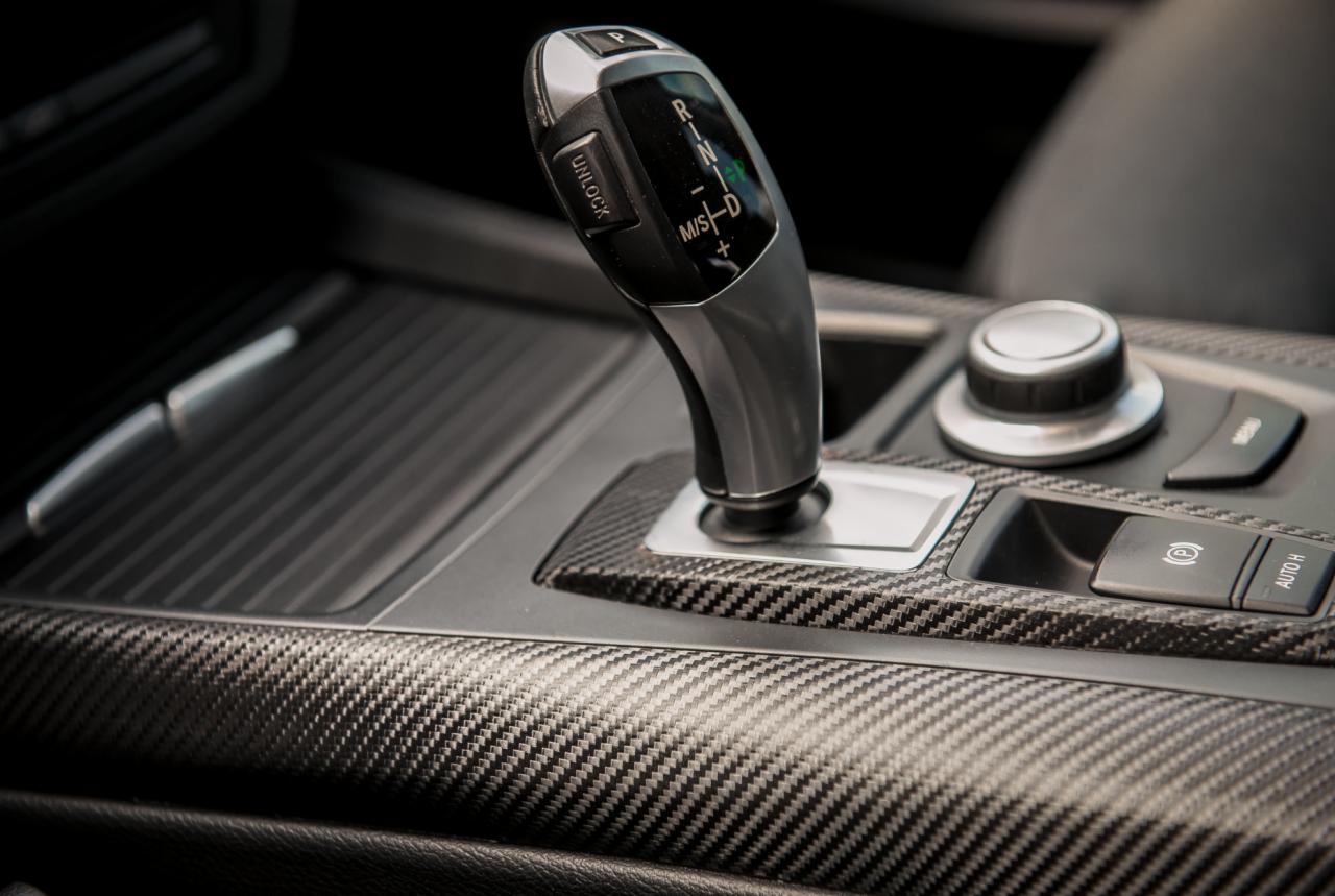 Wnętrze samochodu z dźwignią zmiany biegów i panelem sterowania wykończonym włóknem węglowym.