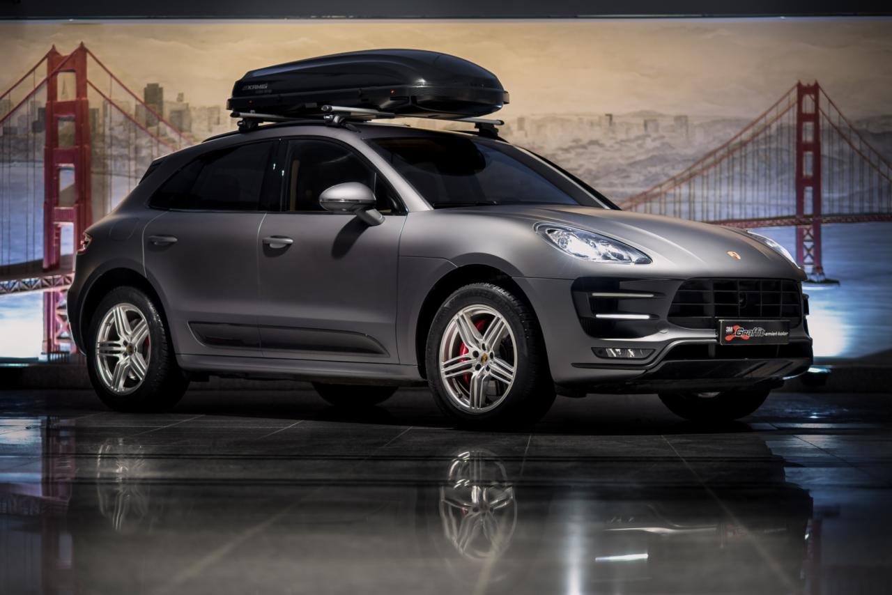 Szary samochód typu SUV z bagażnikiem dachowym na tle panoramy San Francisco, prezentowany w Olsztynie.