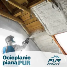 Pracownik w kombinezonie natryskuje izolację na poddaszu, widoczne drewniane elementy konstrukcji dachu i świeżo nałożona warstwa izolacji.