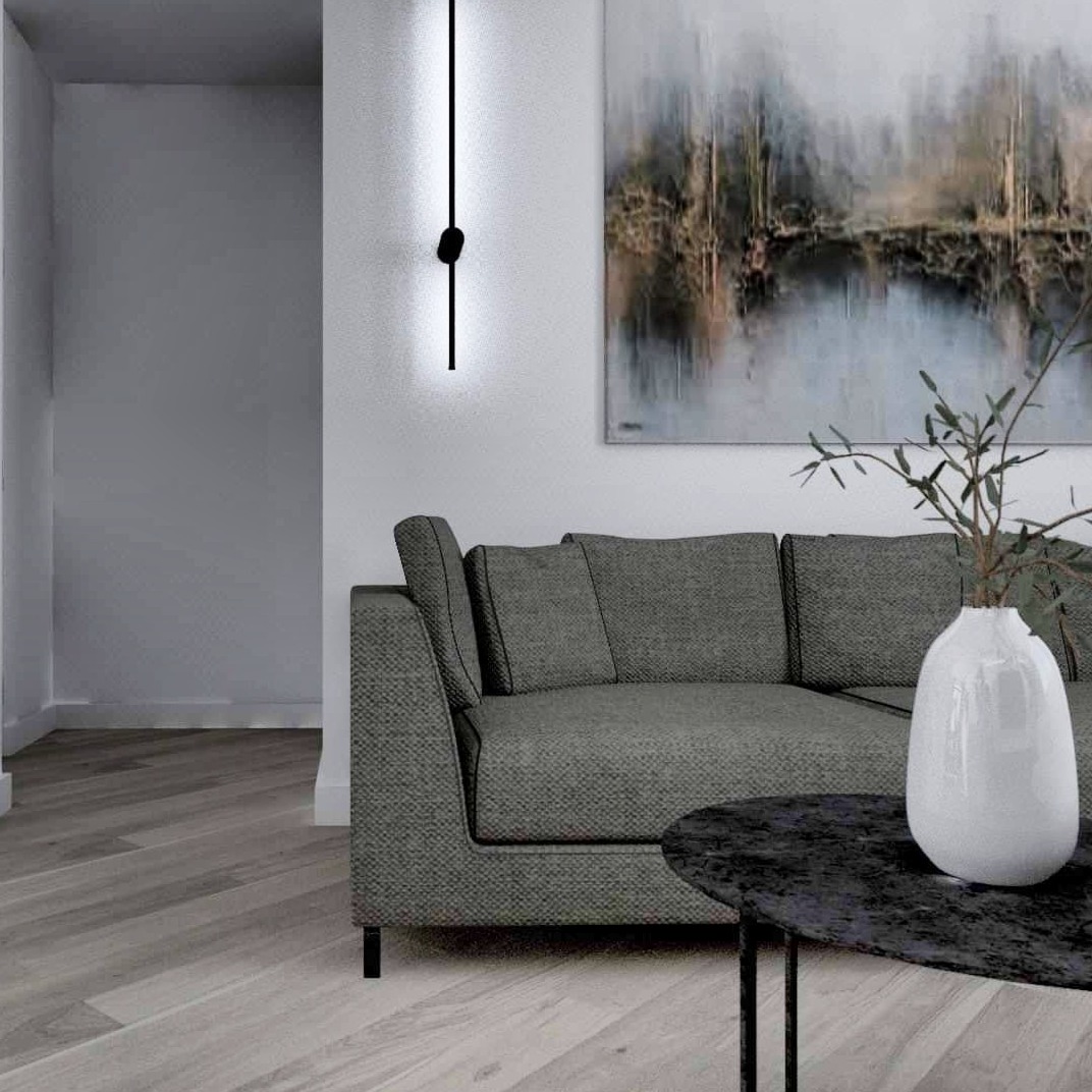 Szary narożnik z poduszkami, czarny stolik kawowy z wazonem i gałązkami, obraz na ścianie i nowoczesna pionowa lampa ścienna w minimalistycznym salonie.