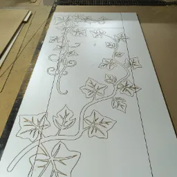 Biały panel z wyfrezowanym wzorem pnącza z liśćmi, tworzony na maszynie CNC w warsztacie w Siedlisku.