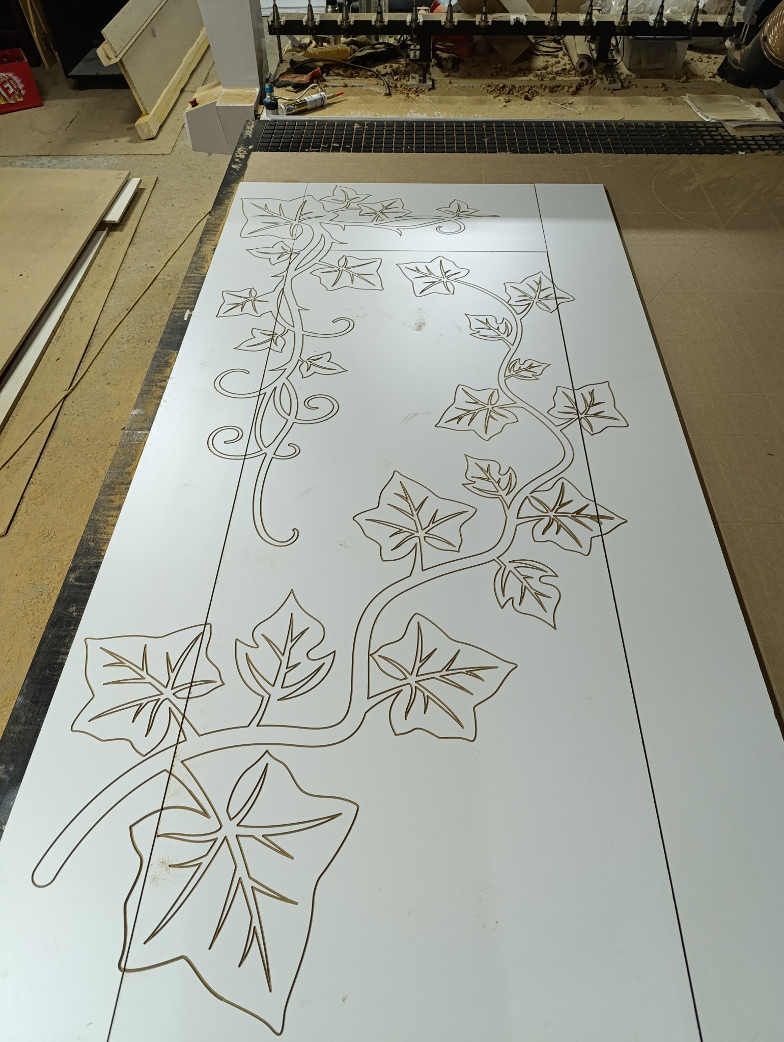 Biały panel z wyfrezowanym wzorem pnącza z liśćmi, tworzony na maszynie CNC w warsztacie w Siedlisku.