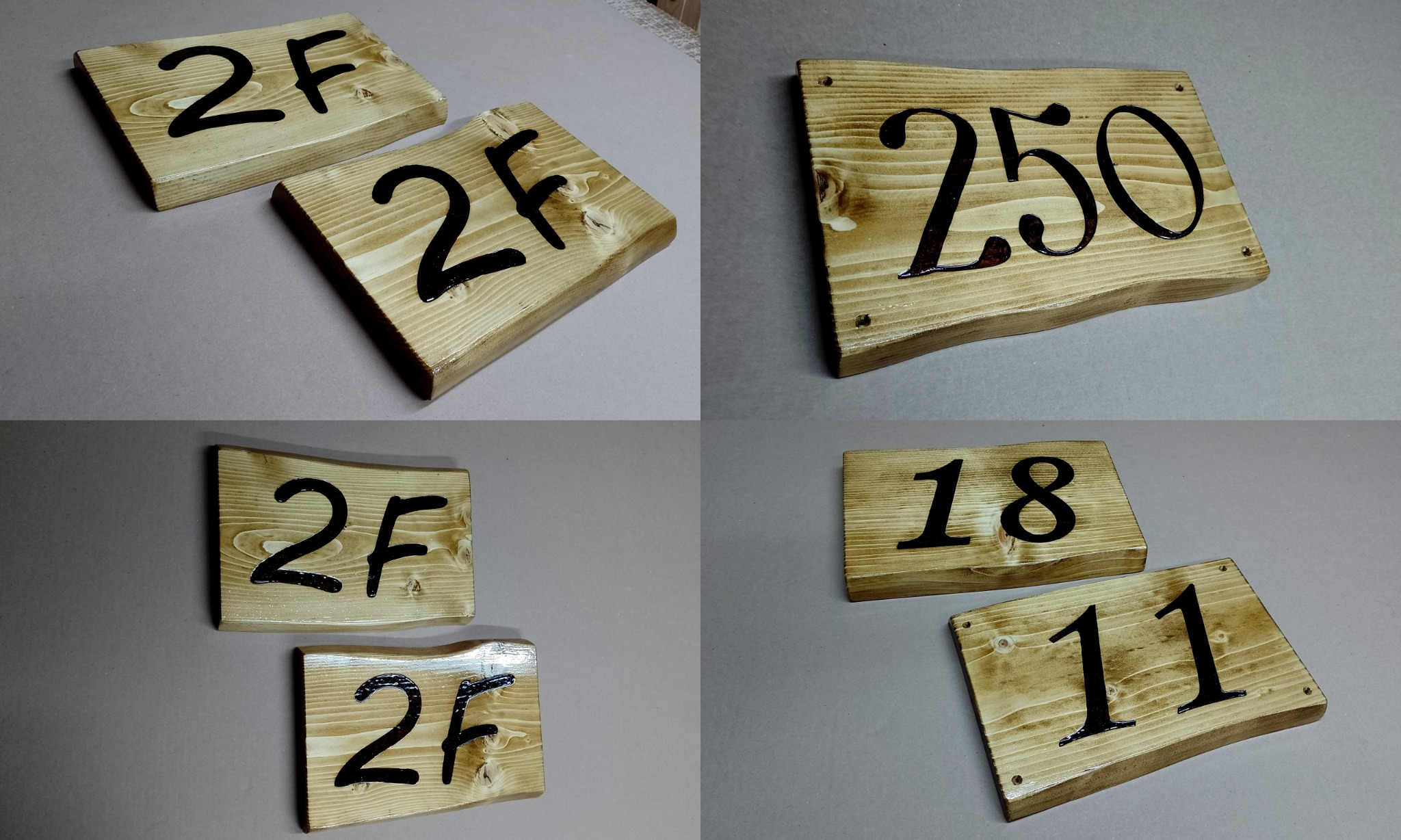 Drewniane tabliczki z numerami i oznaczeniami, wykonane z jasnego drewna z widocznymi słojami, pokryte lakierem, z czarnymi, ręcznie malowanymi numerami: '2F', '250', '18' i '11'.