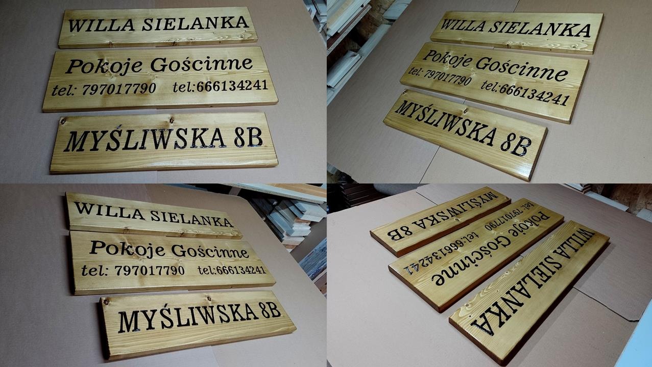 Drewniane tabliczki z wygrawerowanymi napisami: Willa Sielanka, Pokoje Gościnne z numerami telefonów oraz Myśliwska 8B, ułożone na stole w warsztacie.