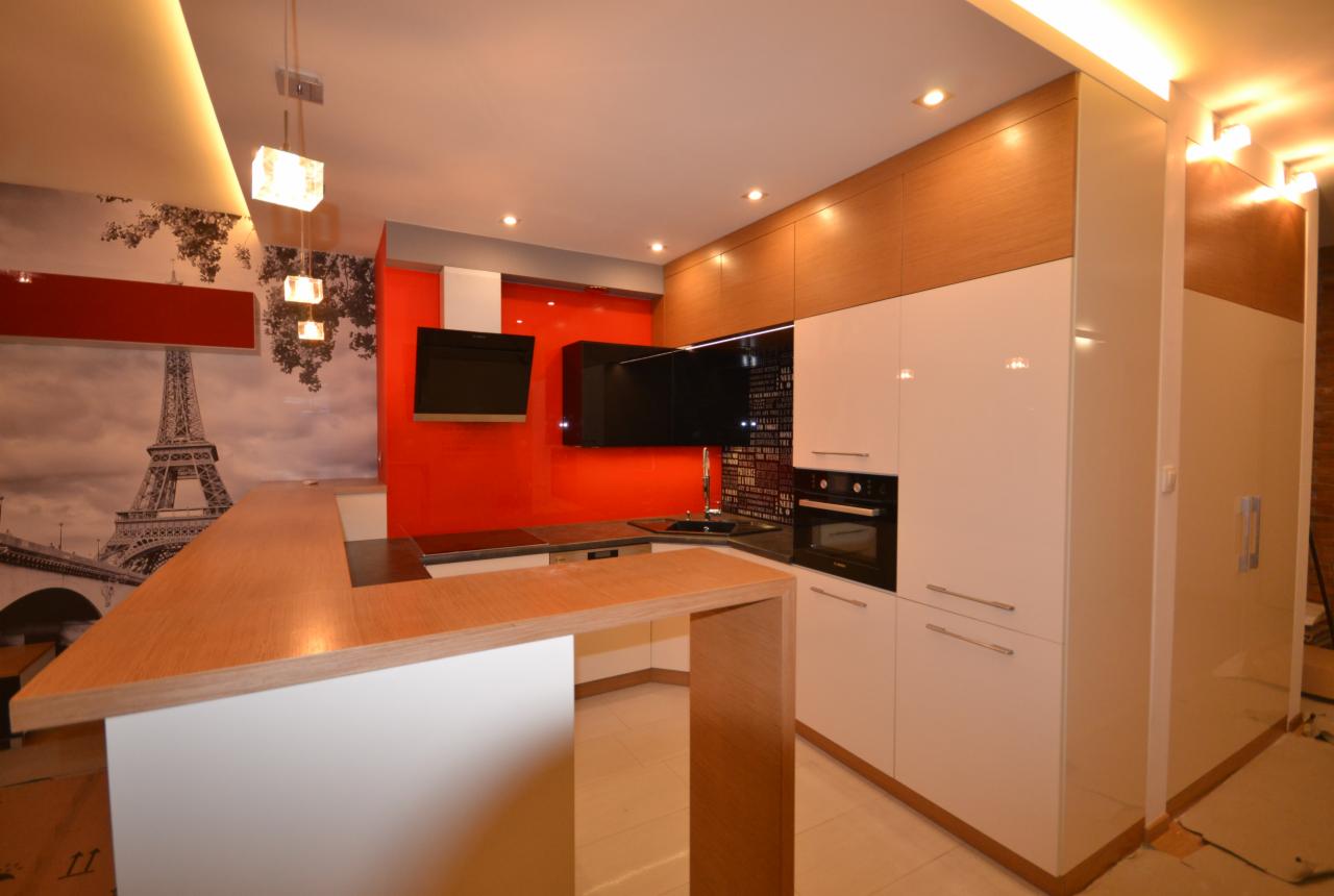 Nowoczesna kuchnia z drewnianym blatem, białymi szafkami i czerwonym panelem ściennym, akcentem paryskim w postaci fototapety z wieżą Eiffla i czarnymi elementami wyposażenia