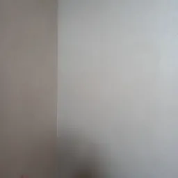 Ściana wewnętrzna po tynkowaniu maszynowym, widoczny narożnik, dwie różne odcienie szarości, drobna faktura tynku.