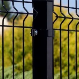 Fragment czarnego ogrodzenia z paneli z metalowym słupkiem na tle zieleni.