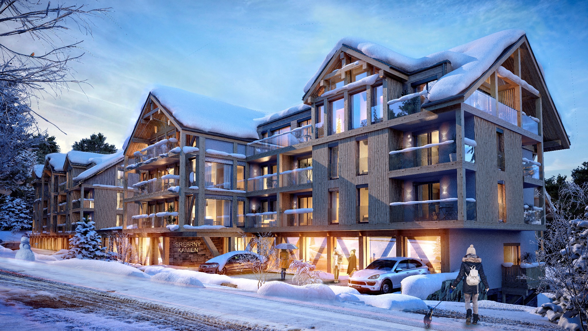 Rezydencja AQUA w Szklarskiej Porębie w zimowej scenerii: wielopiętrowy budynek z drewna i szkła, balkony z balustradami, śnieg na dachu i w otoczeniu, samochody i spacerujący ludzie.