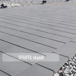 Szara kostka betonowa 'Sparta Skandi' ułożona na posesji, widoczne oświetlenie wzdłuż krawędzi i kamienny obrzeże.