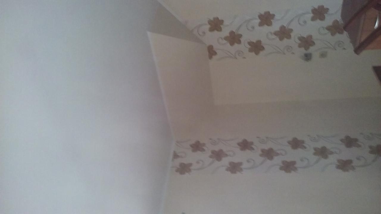 Ściana w pokoju z dekoracyjnym pasem z motywem kwiatowym w kolorze brązowym i szarym, widoczne połączenie ściany z sufitem.