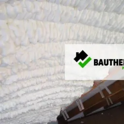 Izolacja poddasza wykonana białą pianką natryskową, widoczne elementy konstrukcji drewnianej oraz logo firmy Bautherm Polska.