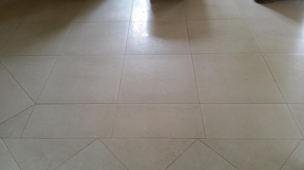 Jasne, matowe płytki podłogowe ułożone w kwadraty i trójkąty, widoczne fugi, z refleksami światła.