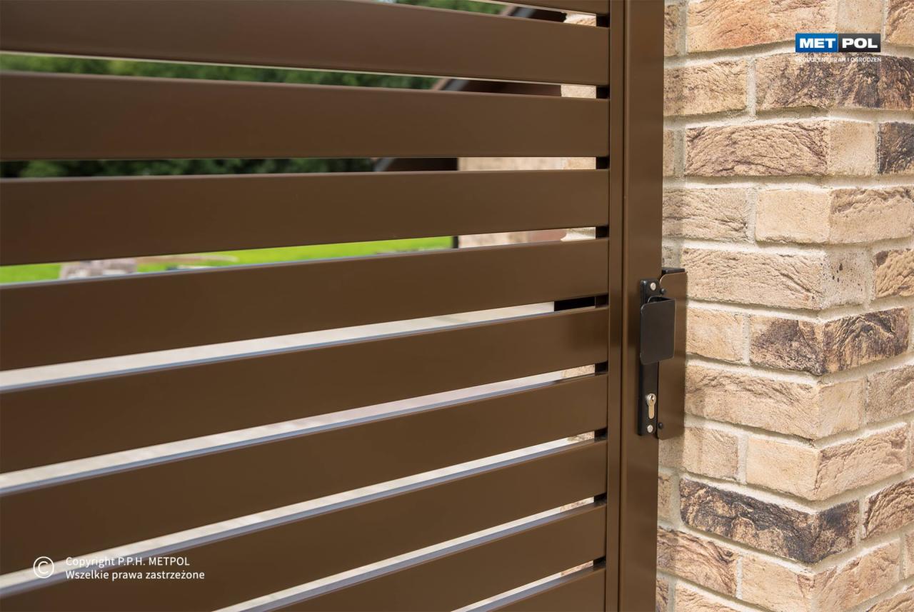 Brązowa brama z poziomych profili, widoczny zamek i fragment murowanego, ceglanego słupka ogrodzeniowego.