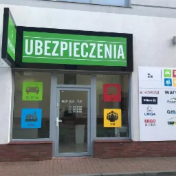 Fasada biura ubezpieczeniowego z dużym zielonym szyldem 'UBEZPIECZENIA', logotypami różnych towarzystw ubezpieczeniowych na ścianie oraz naklejkami na szybach z ikonami samochodu, domu, firmy...