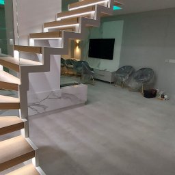 Gallen Sp Zoo - Nowoczesne schody dywanowe z podświetleniem LED, drewnianymi stopniami i szklaną balustradą w minimalistycznym wnętrzu, z widocznym salonem w tle.