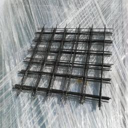 TechFlow3D - Kwadratowa siatka z prętów zbrojeniowych ułożona na folii ochronnej, widoczne refleksy światła.