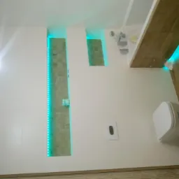 Nowoczesna łazienka z podświetlanymi wnękami, drewnopodobną podłogą i wiszącą toaletą.