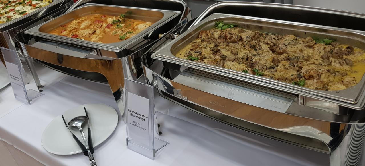 Dwa bemary z potrawami: kurczak w sosie i karkówka w sosie pieczarkowym, biały obrus, talerz z sztućcami.