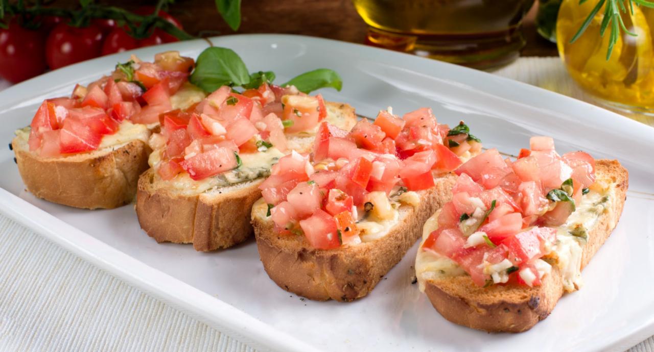 Bruschetta z pomidorami na białym talerzu, oliwa z oliwek i pomidory w tle, klasyczna włoska przekąska.