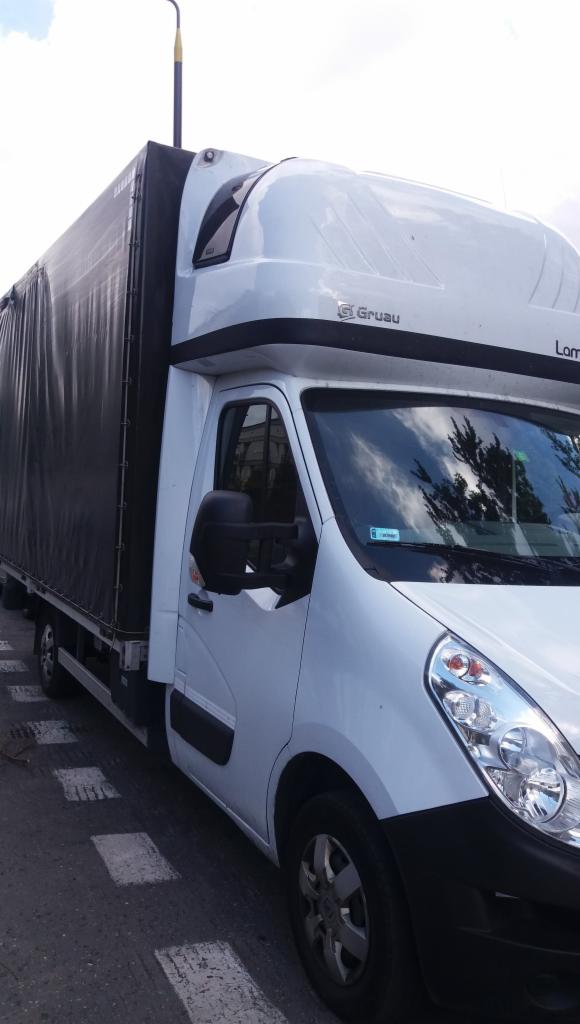 Biały samochód dostawczy z plandeką na parkingu, widoczne logo Gruau.