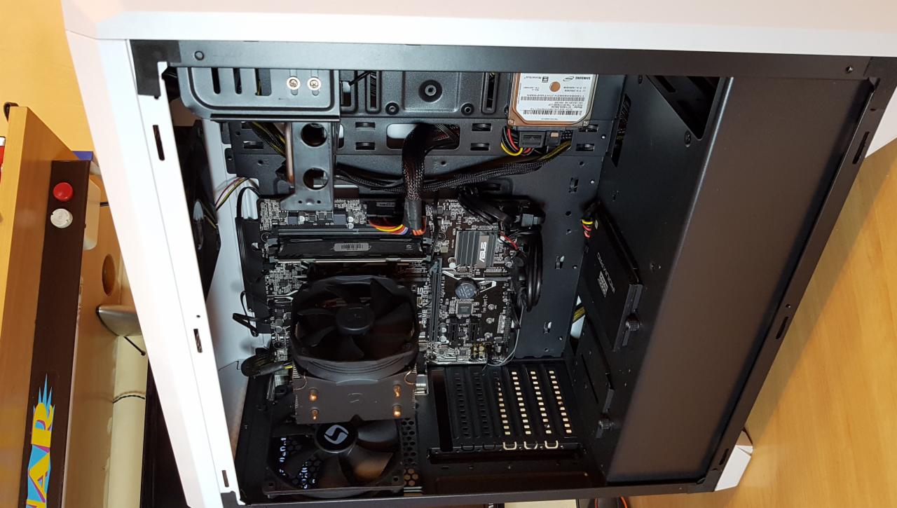 Wnętrze obudowy komputera stacjonarnego z zamontowaną płytą główną ASUS Prime, chłodzeniem procesora z wentylatorem oraz dyskiem twardym Samsung, widoczne kable i złącza