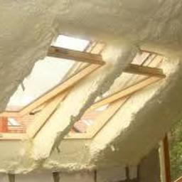 PPHU Embet - Poddasze z oknami dachowymi po izolacji natryskowej, widoczna struktura piany wypełniająca przestrzeń wokół ram okiennych.