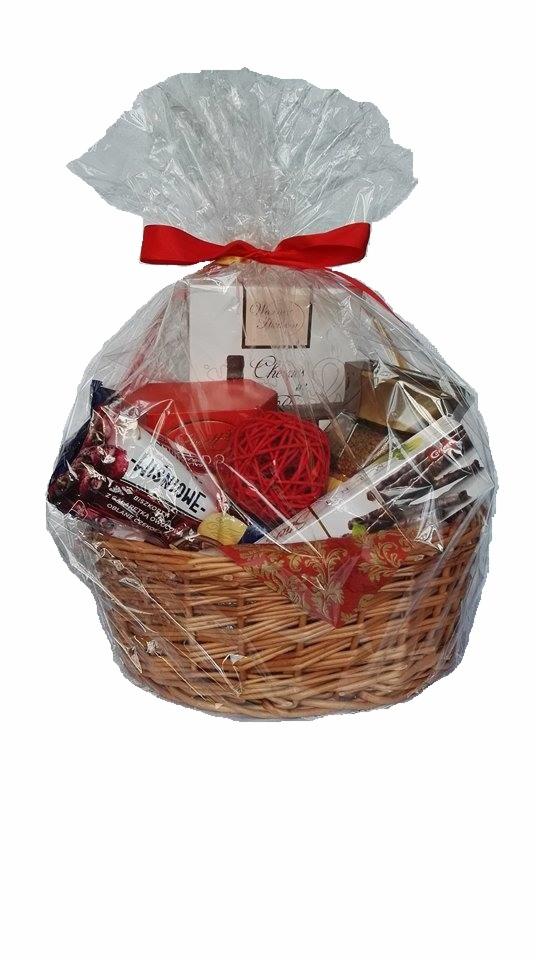 Wiklinowy kosz wypełniony słodyczami, zapakowany w celofan i przewiązany czerwoną wstążką, widoczna czekolada 'Wiśniowe' i pudełko z napisem 'Warmest Season'