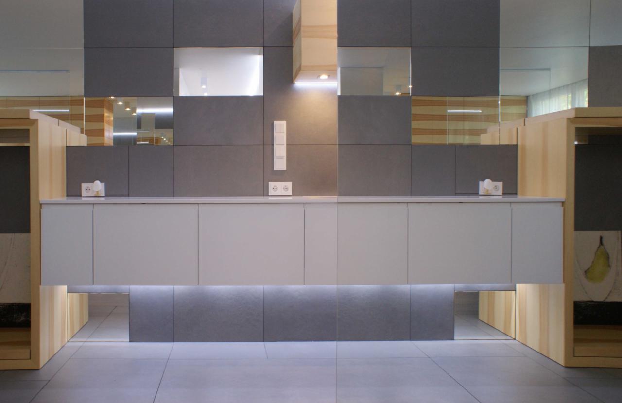 Nowoczesna aranżacja recepcji biurowej z szarymi płytkami, podświetlanym blatem i lustrzanymi wstawkami.