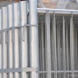 PHU Buildex Krzysztof Puczko - Fragment srebrnego ogrodzenia z metalowych profili pionowych i poziomych, połączonych klamrami, z widocznym słupkiem mocującym.