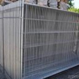 PHU Buildex Krzysztof Puczko - Stos ocynkowanych, spawanych paneli ogrodzeniowych, widoczne złącza i niewielka etykieta na jednym z paneli, na tle drzew i sterty drewna.