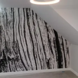 Ściana pokoju po remoncie z fototapetą imitującą korę drzewa, skośny sufit i oświetlenie LED w suficie podwieszanym