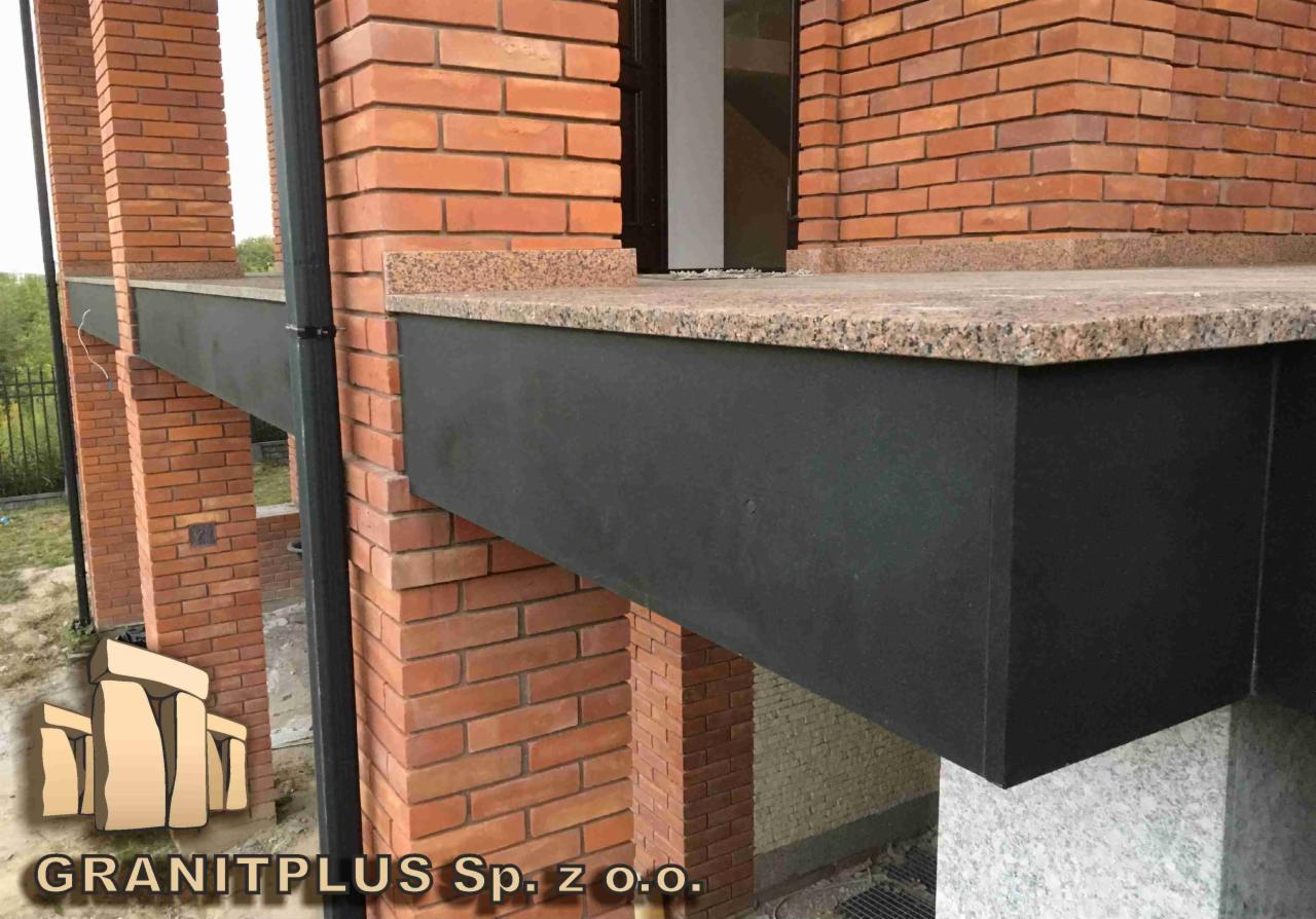 Wykończenie elewacji budynku z cegły klinkierowej z elementami granitowymi, widoczny czarny pas pod parapetem z blatem z jasnego granitu.