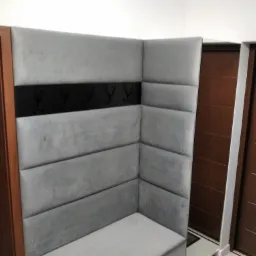 Szary, tapicerowany narożnik z wieszakami w przedpokoju, widoczne drzwi z drewnianą okleiną.