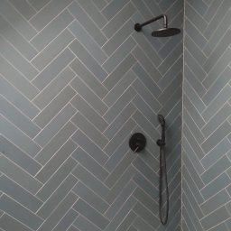 ARKADIUSZ LIPA ARBUD - Ściana kabiny prysznicowej wyłożona niebiesko-szarą glazurą w jodełkę z czarną armaturą w Cieszynie.