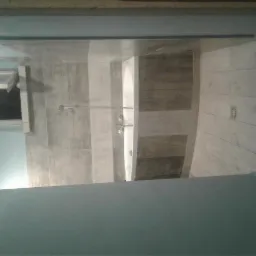 Wykończona łazienka z kabiną prysznicową typu walk-in, wyłożona płytkami w odcieniach szarości i beżu, z odpływem liniowym w podłodze i oknem dachowym.