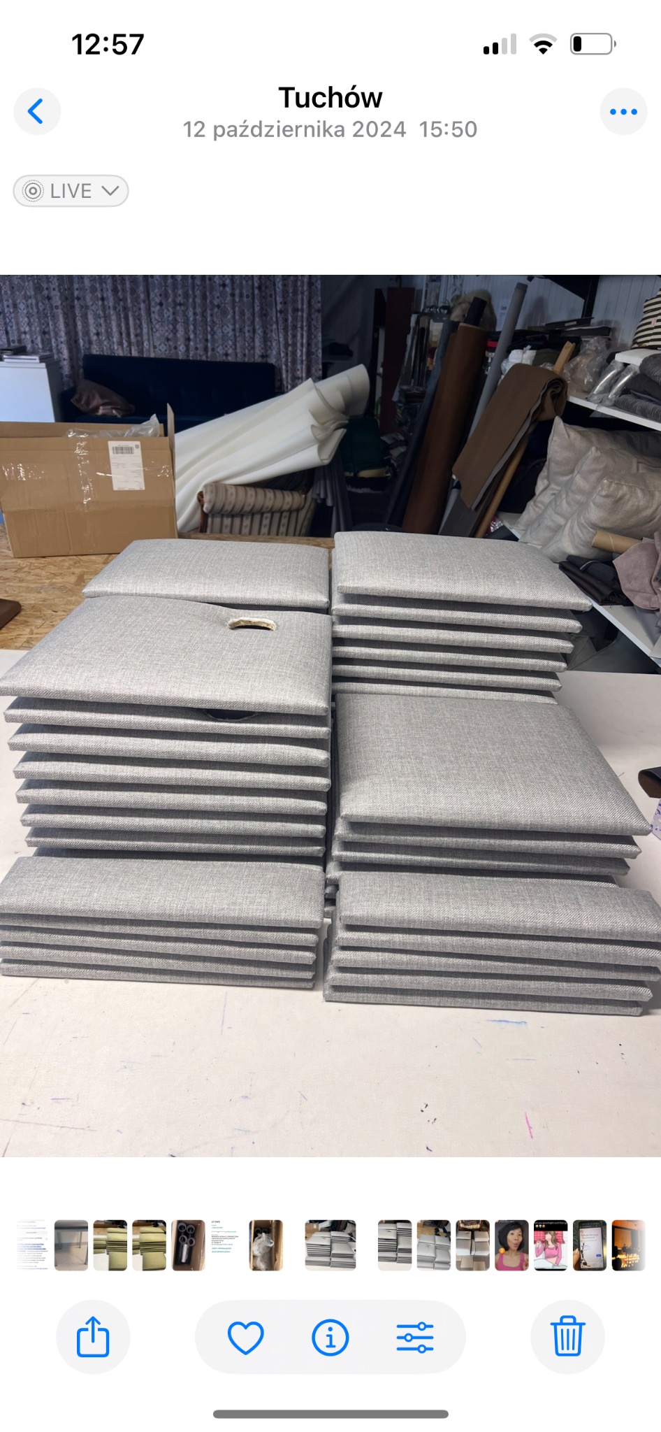 Stosy gotowych, szarych poduszek na krzesła z uchwytami, ułożone na stole w warsztacie. W tle widoczne materiały i narzędzia.