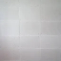 Ściana wykończona białymi panelami imitującymi beton architektoniczny, z widoczną strukturą i śladami po szalunku, oraz fragment podłogi wyłożonej panelami drewnopodobnymi.