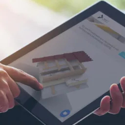 Osoba przegląda na tablecie model 3D przekroju dachu z izolacją termiczną, prezentowany na stronie internetowej producenta.