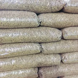 Stos work&oacute;w z pelletem drzewnym, przezroczyste opakowania, lekko rozmyte tło.