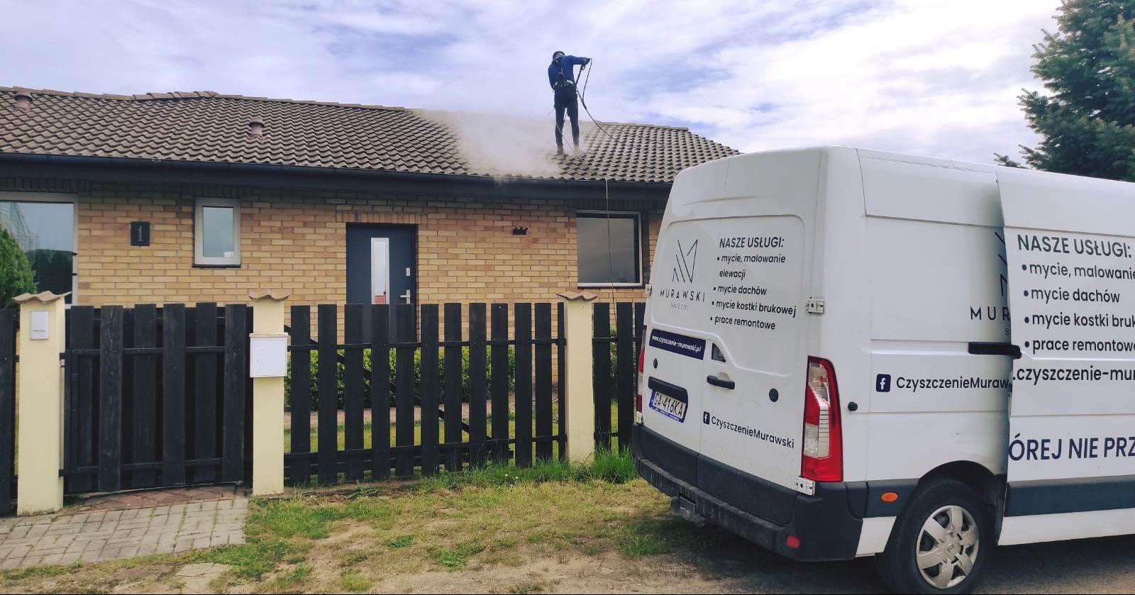 Czyszczenie dachu domu jednorodzinnego pod ciśnieniem przez pracownika w uprzęży. W tle zaparkowany biały bus z reklamą firmy czyszczącej.