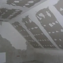 Montaż płyt karton gips w skosach poddasza w Nowej Soli, widoczne łączenia płyt i wstępne szpachlowanie, okno PCV z grzejnikiem pod spodem.