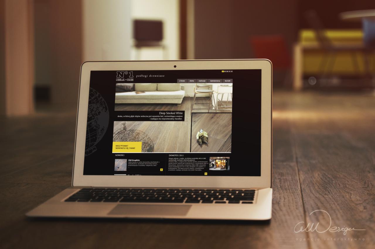 Laptop z otwartą stroną internetową prezentującą ofertę podłóg drewnianych firmy z Raciborza, umieszczony na drewnianym blacie, z widocznym logo agencji interaktywnej w prawym dolnym rogu.