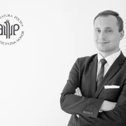 Portret uśmiechniętego mężczyzny w garniturze, z założonymi rękami, na jasnym tle z logo Adwokatury Polskiej.