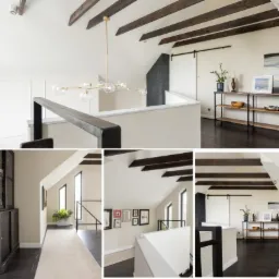 Przestronny hall z drewnianymi belkami stropowymi, nowoczesnym oświetleniem i przesuwnymi drzwiami stodołowymi, uzupełniony minimalistyczną konsolą z dekoracjami.