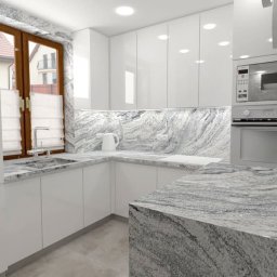 MAKAREWICZ Projekt - Nowoczesna biała kuchnia z blatem i backsplashiem z szarego marmuru, widok na okno z roletami rzymskimi i zabudowany piekarnik z mikrofalówką.