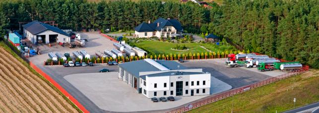 Widok z lotu ptaka na bazę firmy transportowej z budynkami biurowymi, warsztatem i zaparkowanymi cysternami oraz ciężarówkami.