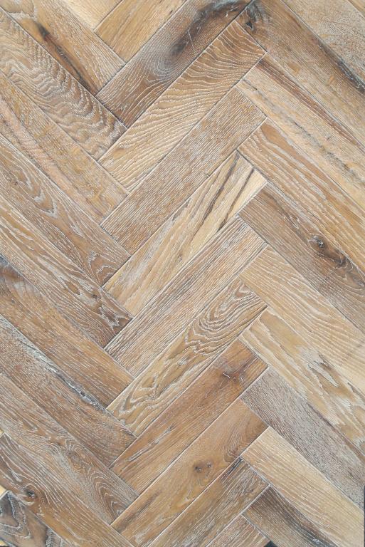 Parkiet ułożony w jodełkę francuską, deski w odcieniach brązu z widoczną strukturą drewna i delikatnym efektem postarzenia, ujęcie z góry.