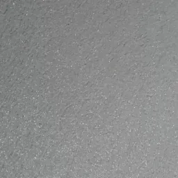 Szara, drobnoziarnista powierzchnia ściany, widoczna pod lekkim kątem, z delikatnym połyskiem.