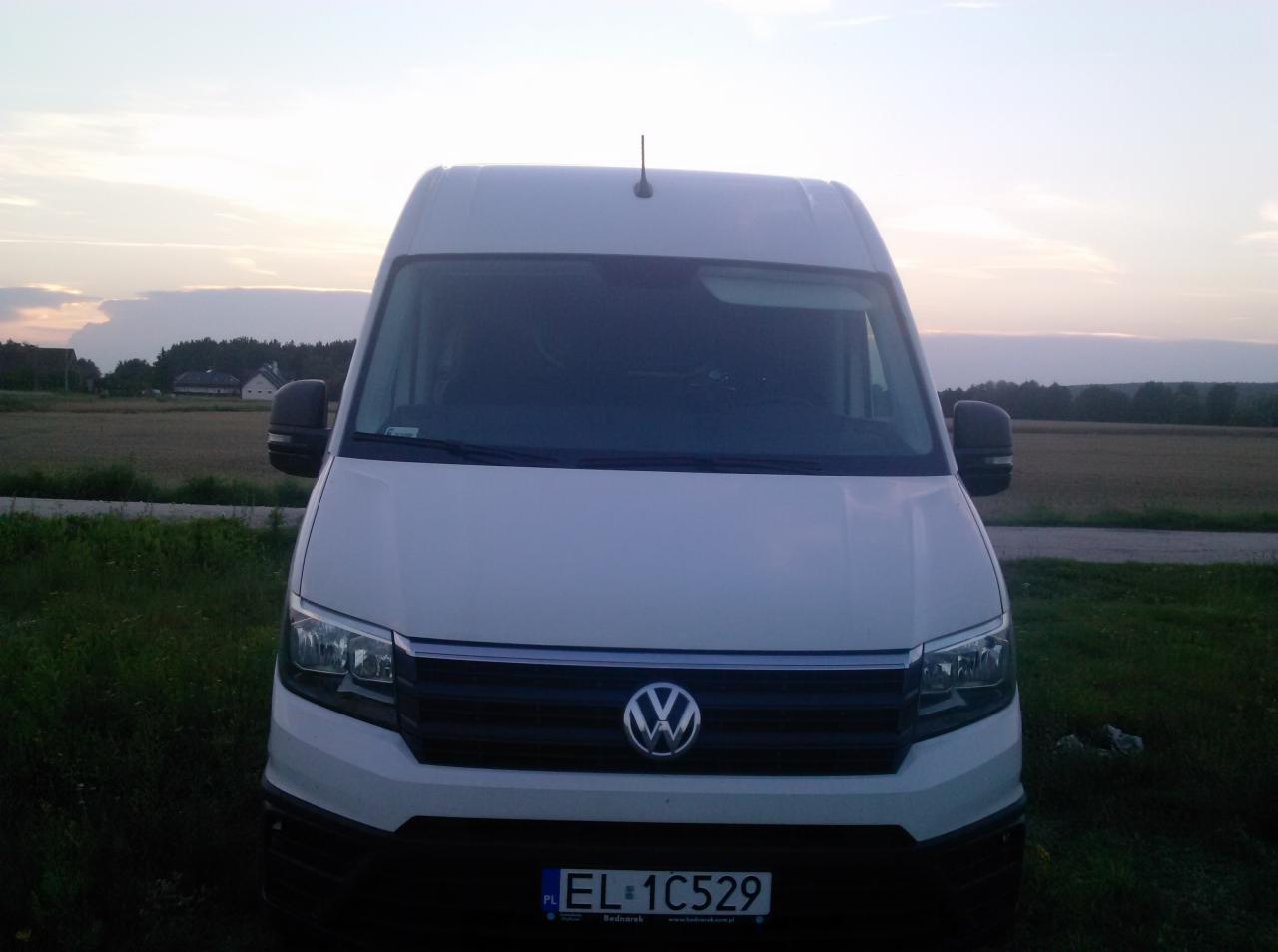 Biały Volkswagen Crafter zaparkowany na łące o zmierzchu, widok z przodu, widoczna tablica rejestracyjna EL 1C529
