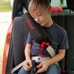 PIĄTKA bis - Chłopiec śpi w samochodzie, opierając głowę o ochraniacz na pas z wyhaftowanym imieniem 'Kamil', trzymając w rękach zabawkę.